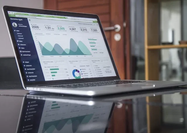 Laptop on a desk displaying a financial analytics dashboard with charts and key metrics